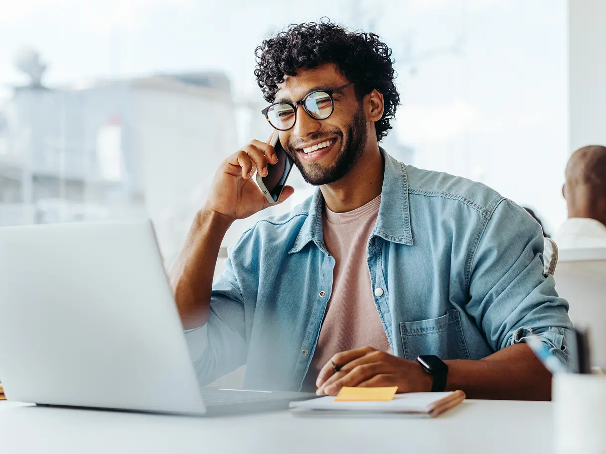 Guy talking on phone in front of laptop screen