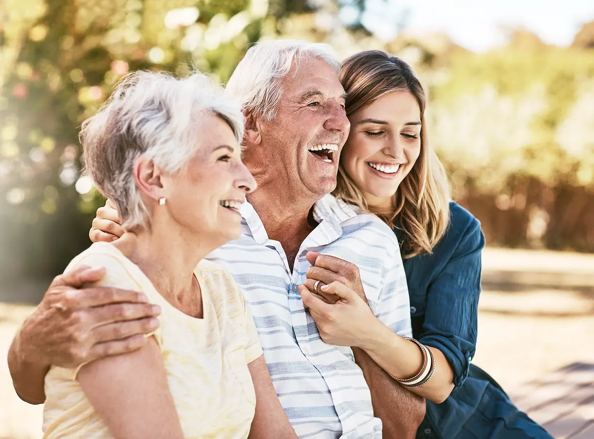 Hug Grandparents with granddaughter in backyard smiling