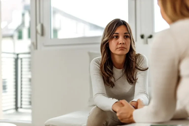 Young woman sitting on white chair having a conversation with specialist